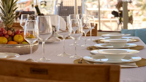 Close-up of the elegantly laid dining table on the Gulet Linda, with wine glasses and a fruit basket.